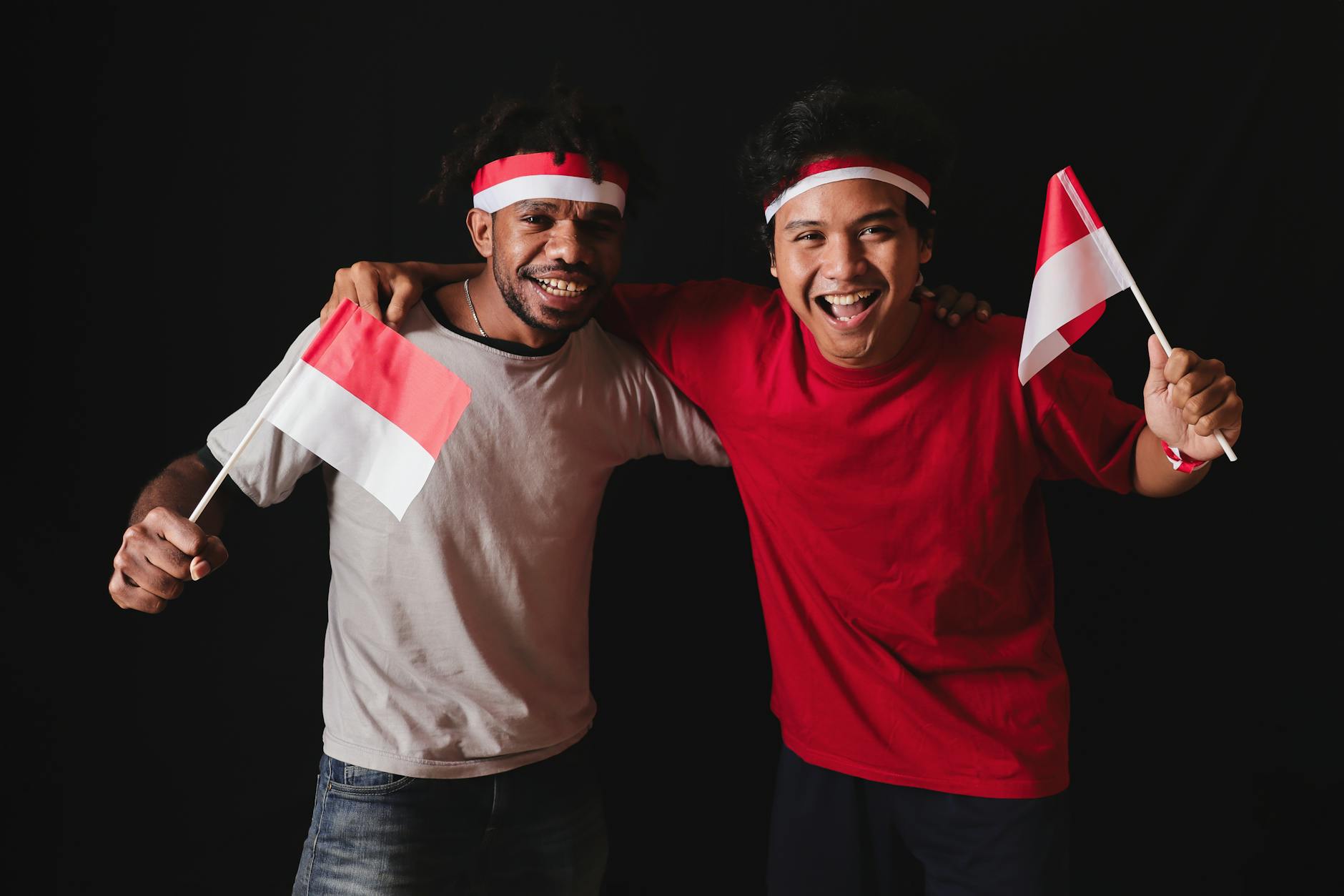 Two young men celebrate Indonesian unity with flags and smiles in Yogyakarta.