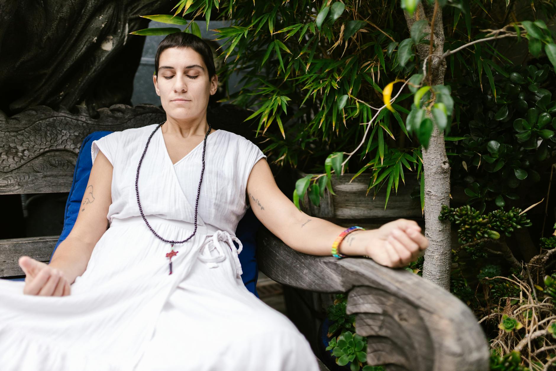 A woman in white dress meditates outdoors, embodying calmness and mindfulness.