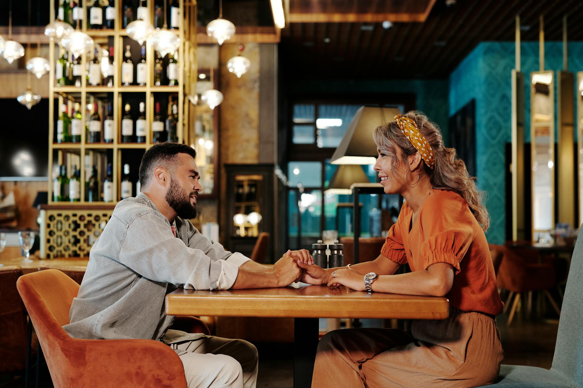 A couple enjoying a romantic date, holding hands in a stylish café setting.