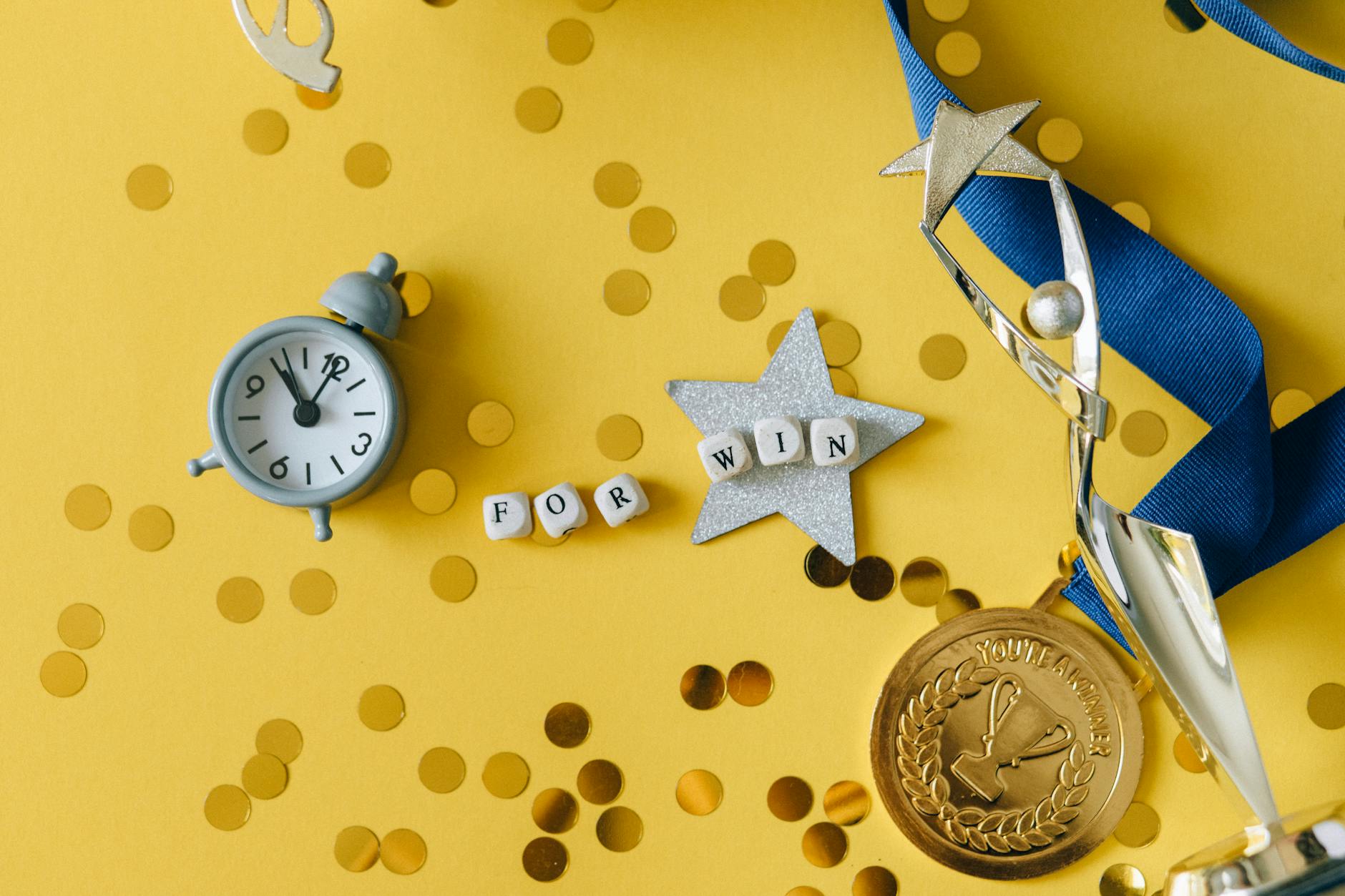 Conceptual flat lay of a trophy, medal, and clock with 'FOR WIN' letters, symbolizing victory and achievement.