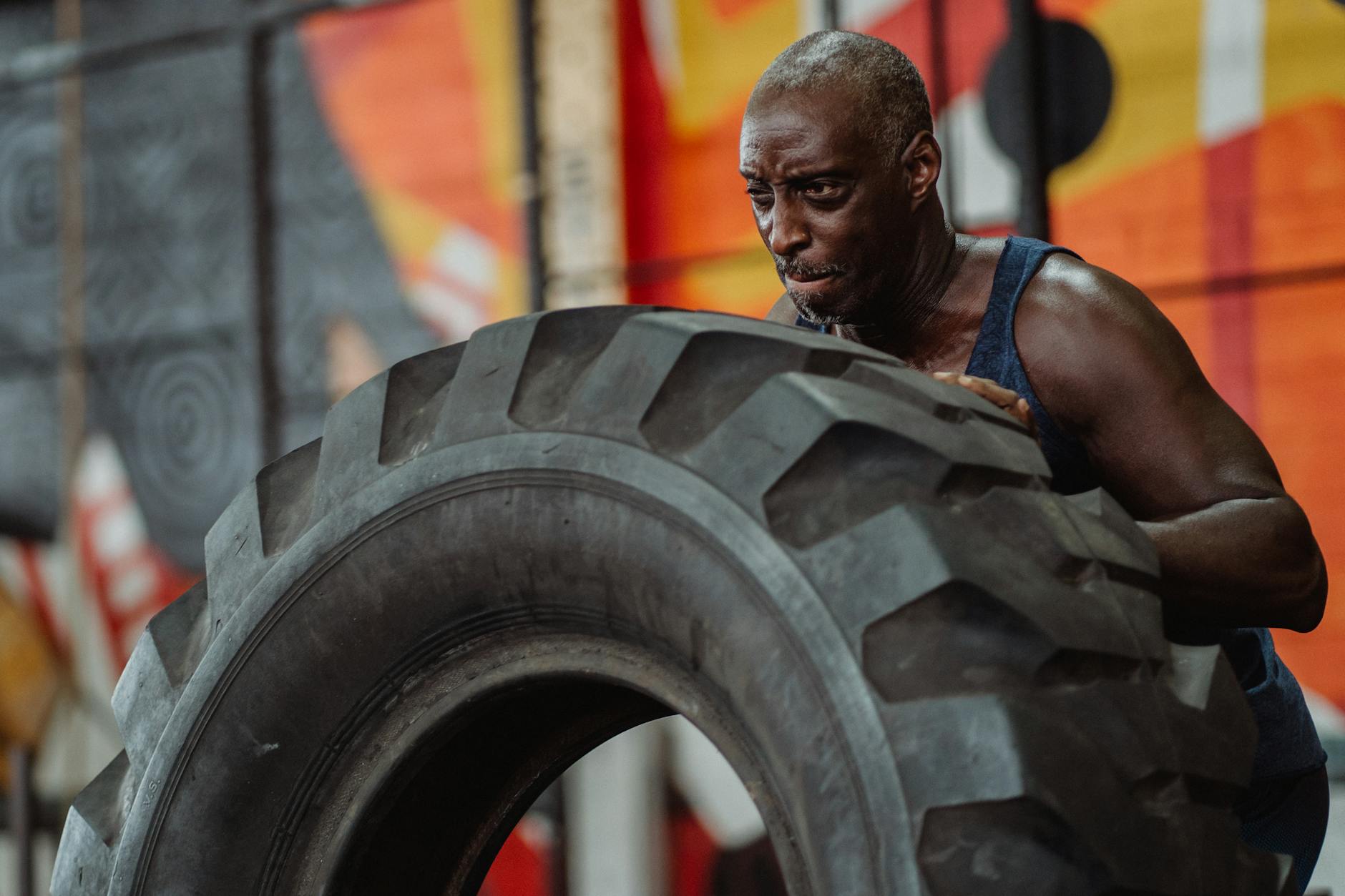 Focused man engaging in intense tire workout at gym.