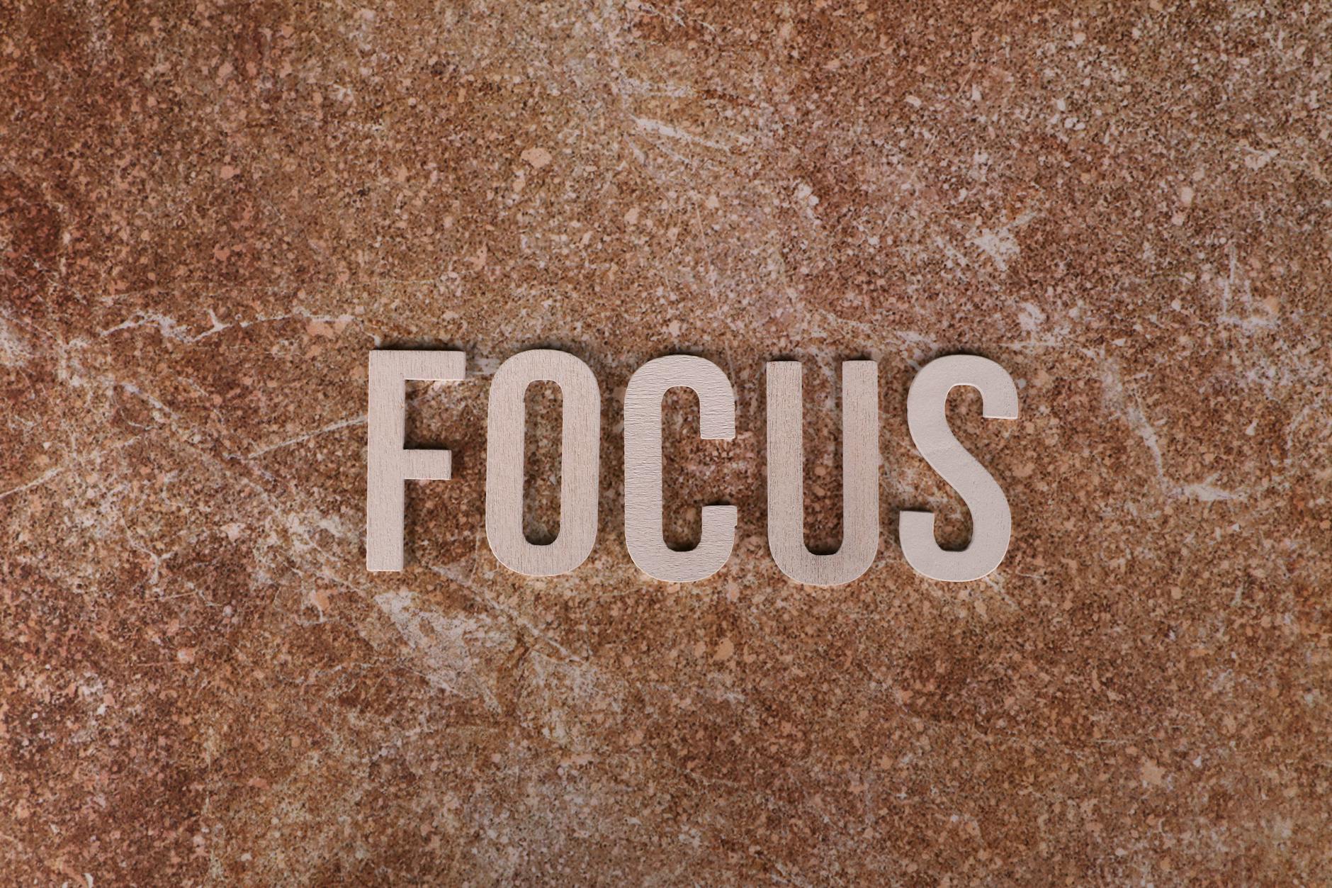 Wooden letters spelling 'FOCUS' on a textured brown surface for emphasis.