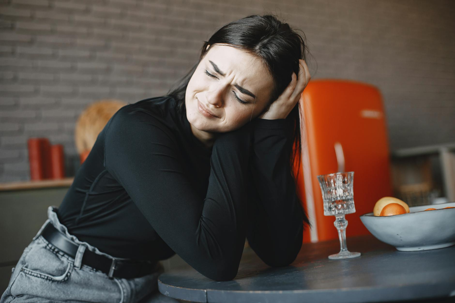 A woman displays emotional distress while sitting indoors, conveying feelings of anxiety and worry.