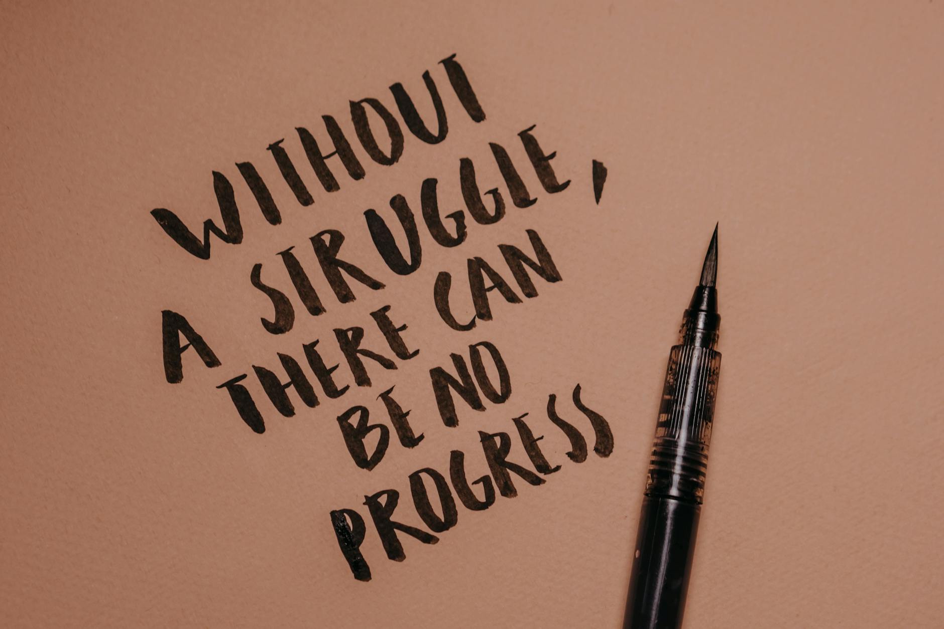 Handwritten motivational quote using a brush pen on a textured background for inspiration.