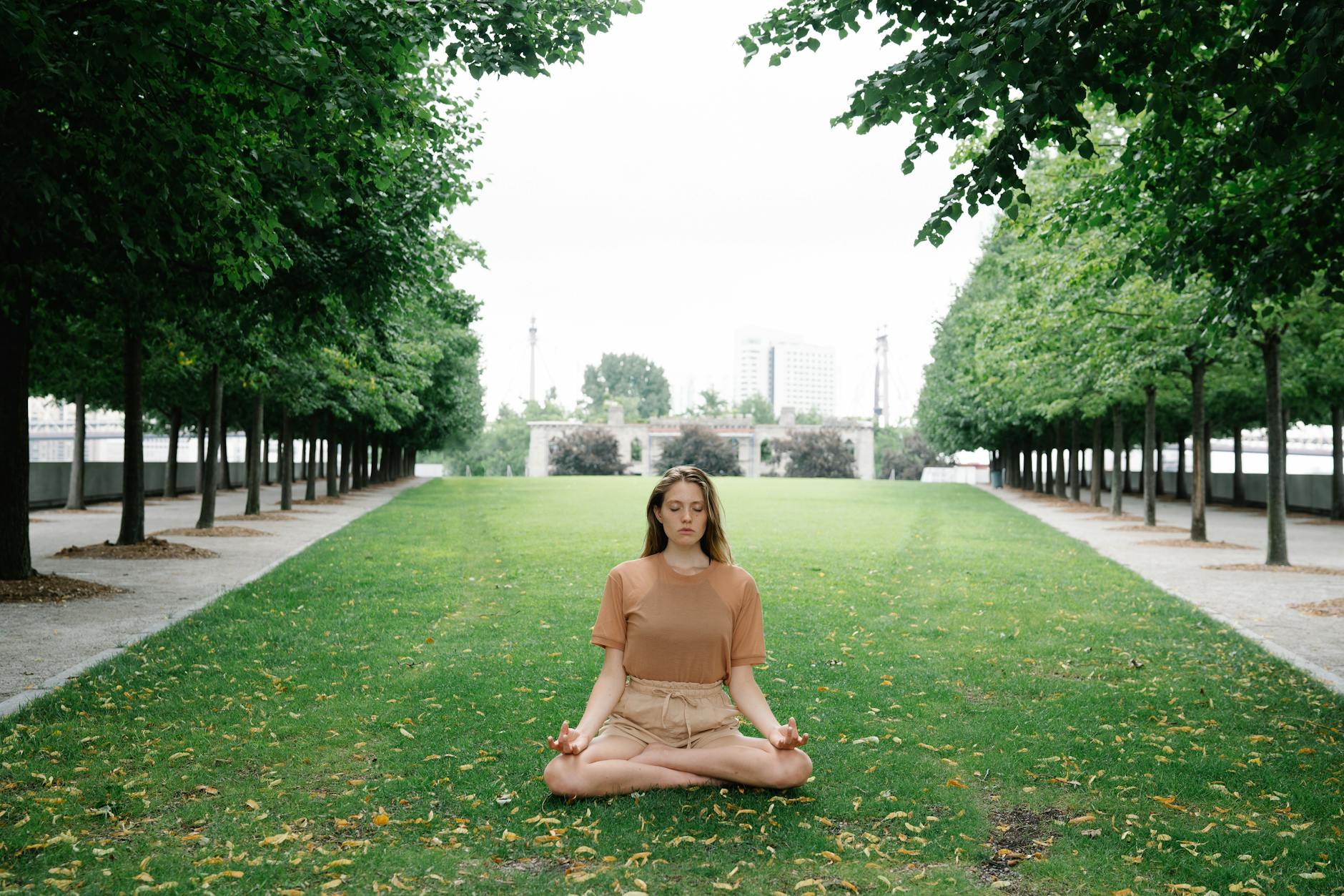 Woman practicing yoga meditation in a peaceful green park setting