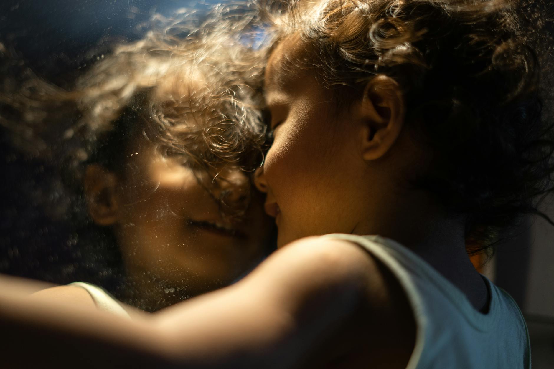 A child joyfully embraces their reflection, capturing innocence and curiosity.