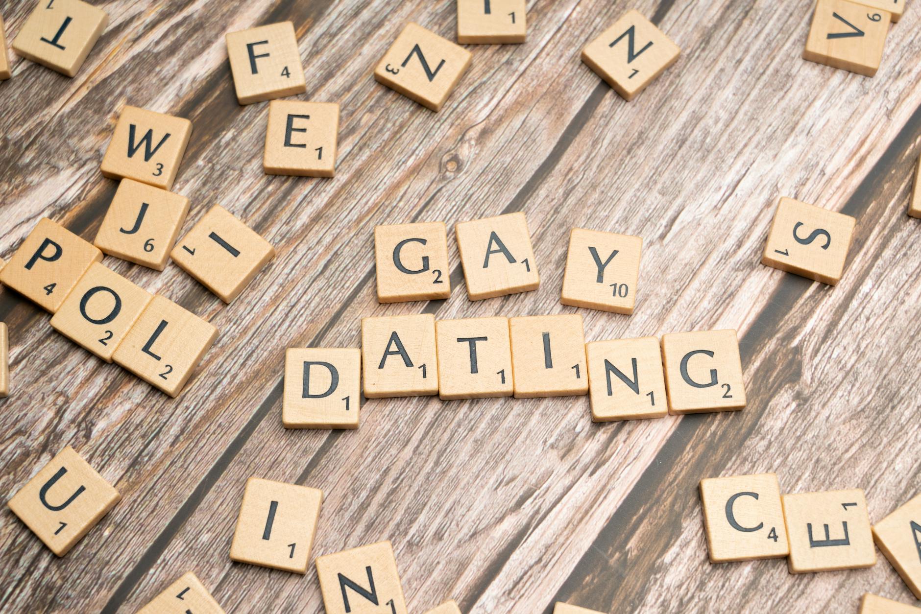 Scrabble tiles spelling 'Gay Dating' on a rustic wooden background, representing LGBTQ themes.