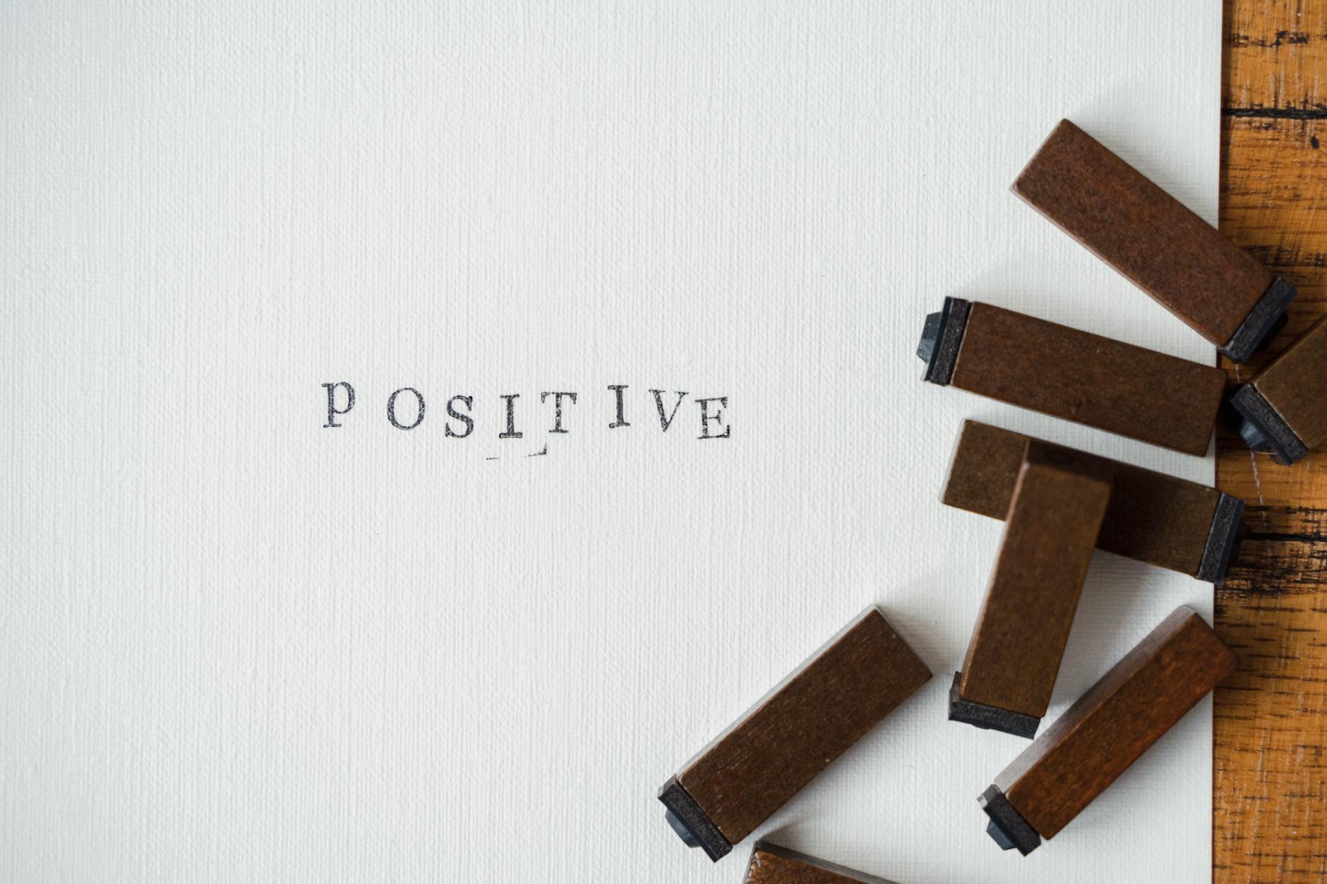 Close-up of 'Positive' word created with vintage wooden letter stamps on textured paper.