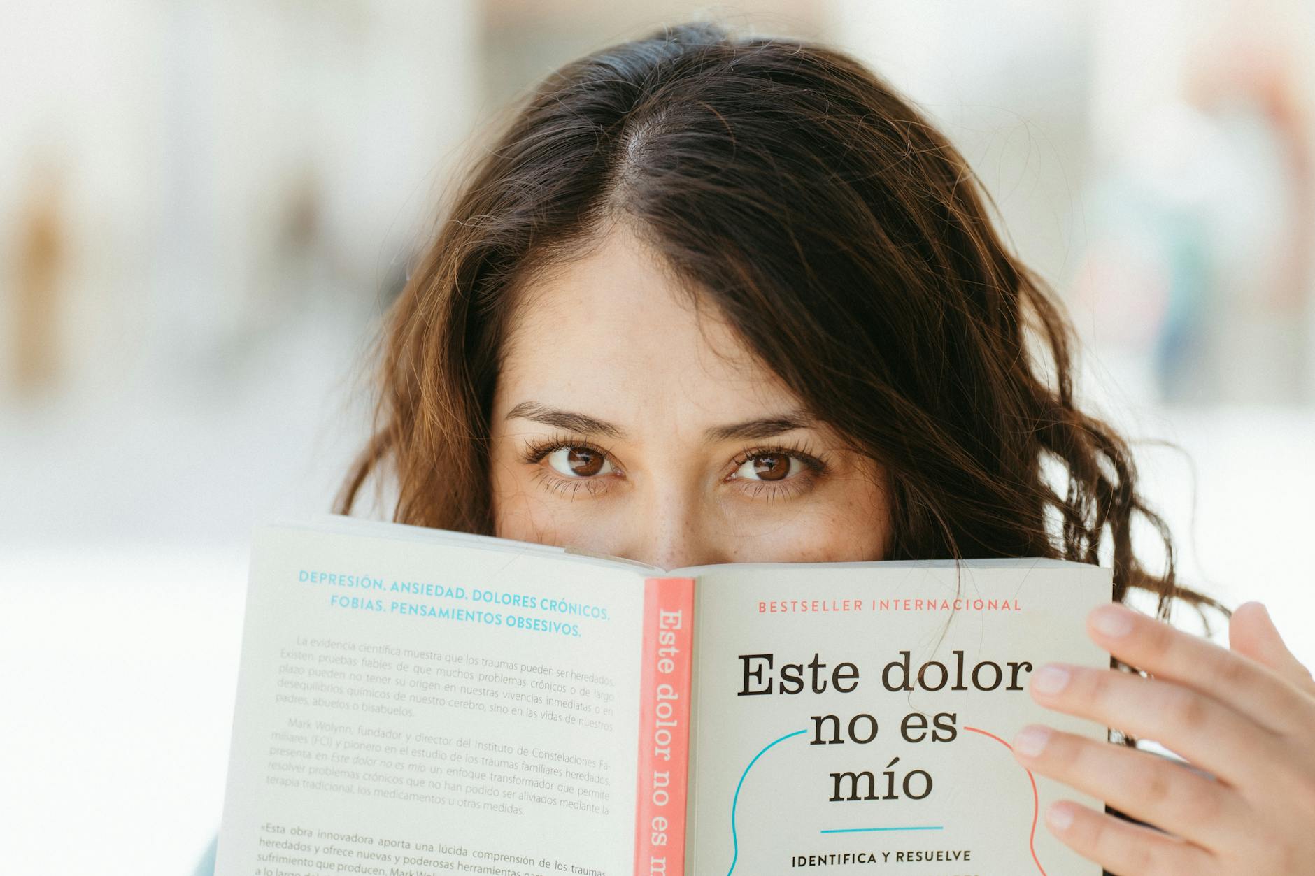 A woman reading a book titled 'Este dolor no es mío', focusing on mental health awareness.