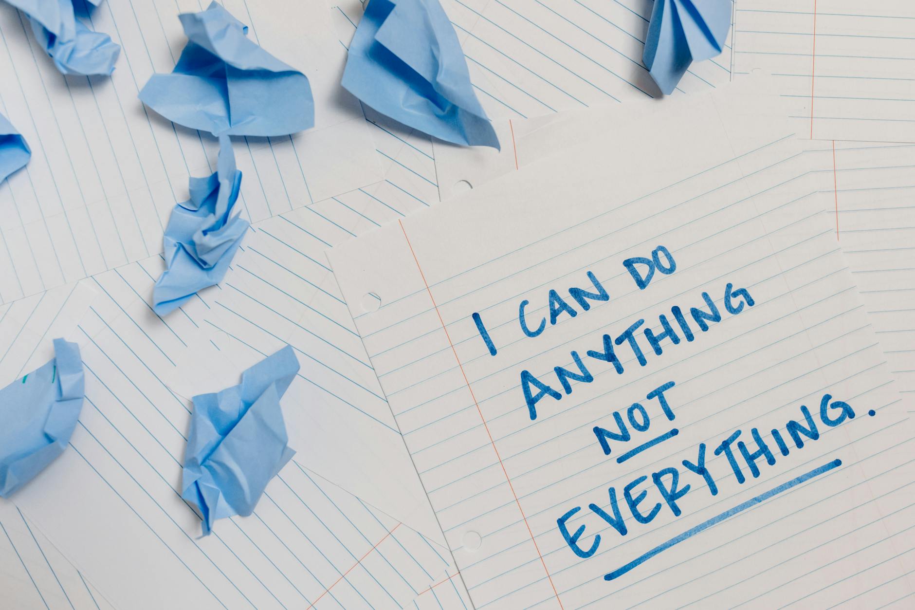 Inspirational quote on paper surrounded by crumpled blue sheets, conveying motivation.